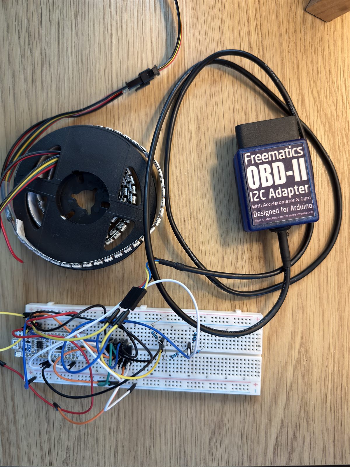 Breadboard bench setup with an STM32 Nucleo-32, an OBD-II I2C adapter, and an SK9822 LED strip on its reel